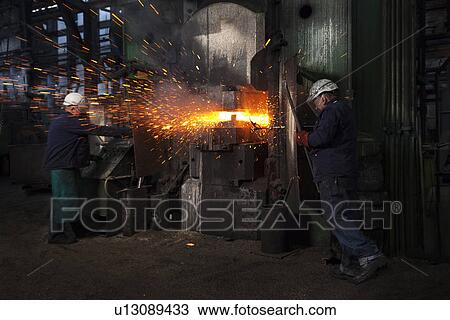 Stock Image - Sparks fly as counterblow hammer forms flight bar, the counterblow hammer forges by striking from both above and below mining component. Fotosearch