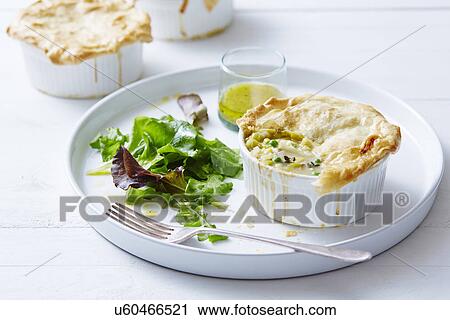 Stock Image - Still life of chicken, leek and pea pies. Fotosearch