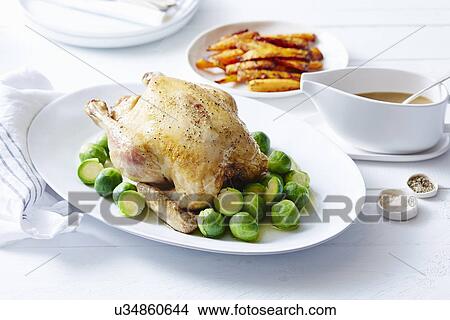 Picture - Still life of roast chicken with brussel sprouts and carrots. Fotosearch