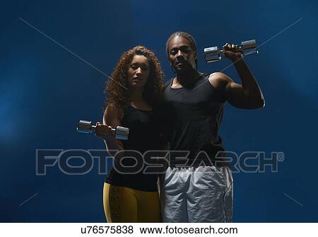 Studio portrait of young male and female holding dumb bells View Large Photo Image Stock Photo - Studio portrait of young male and female holding dumb bells. Fotosearch
