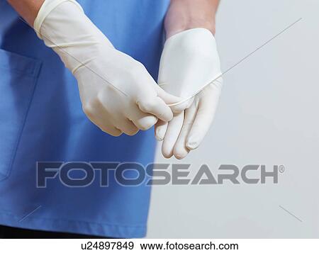Stock Photo - Surgeon putting on latex gloves. Fotosearch