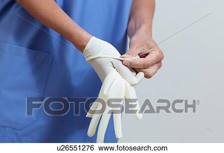Stock Photograph - Surgeon putting on latex gloves. Fotosearch