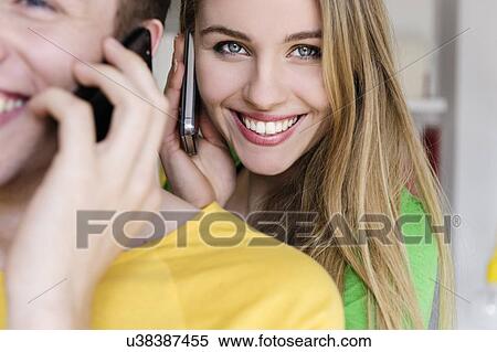 Stock Photography - Teenage girl on cell phone with man in foreground. Fotosearch