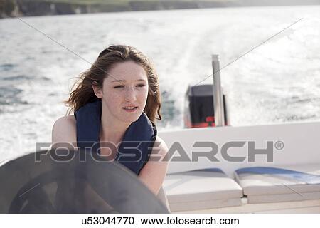 Stock Image - Teenager driving speedboat. Fotosearch
