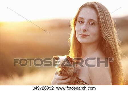Teenager standing in field at dusk holding domestic dog View Large Photo Image Stock Image - Teenager standing in field at dusk holding domestic dog. Fotosearch