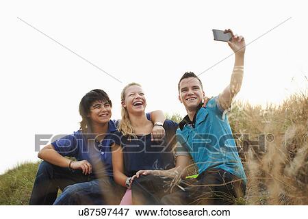 Teenagers sitting on sand dune taking self portrait photograph View Large Photo Image Stock Photo - Teenagers sitting on sand dune taking self portrait photograph. Fotosearch