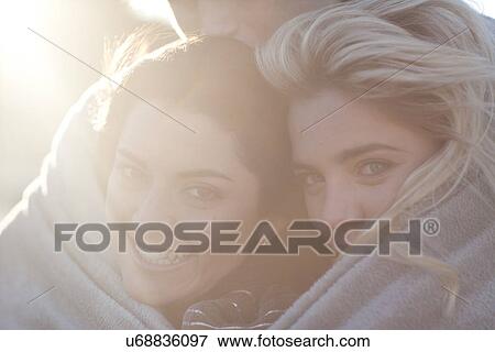 Stock Photo - Three friends huddled up in blanket. Fotosearch