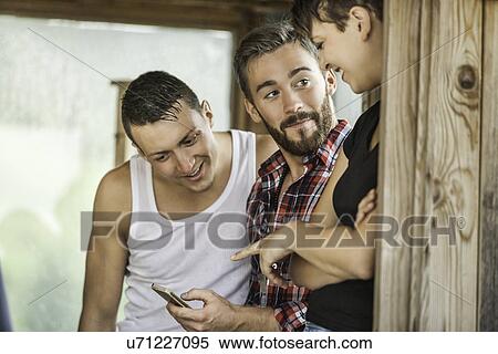 Stock Photography - Three friends looking at mobile phone. Fotosearch