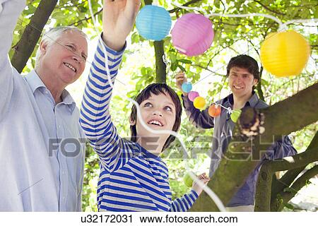 Three generation family putting fairy lights in tree View Large Photo Image Stock Image - Three generation family putting fairy lights in tree. Fotosearch