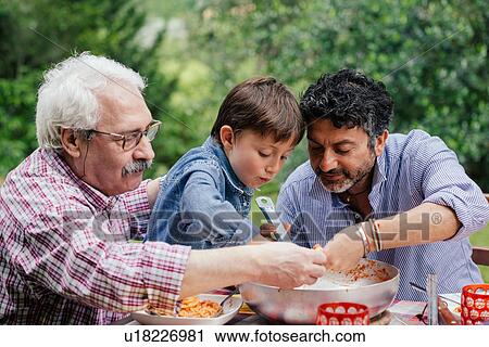 Three generations of male family enjoying a meal together View Large Photo Image Stock Image - Three generations of male family enjoying a meal together. Fotosearch