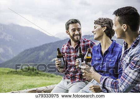 Three young adult friends drinking beer on fence, Tyrol Austria View Large Photo Image Stock Photography - Three young adult friends drinking beer on fence, Tyrol Austria. Fotosearch