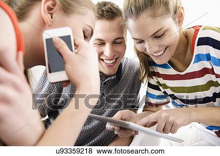 Three young adult friends looking at digital tablet View Large Photo Image Stock Photo - Three young adult friends looking at digital tablet. Fotosearch