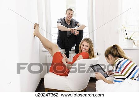 Three young adult friends lounging in bedroom View Large Photo Image Stock Image - Three young adult friends lounging in bedroom. Fotosearch