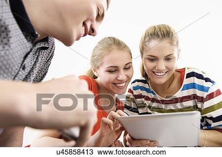 Stock Image - Three young adult friends with digital tablet. Fotosearch
