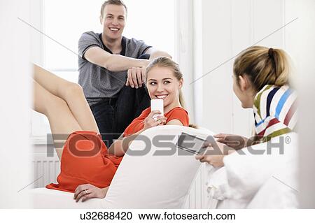Three young adult friends with mobiles and digital tablet in bedroom View Large Photo Image Stock Image - Three young adult friends with mobiles and digital tablet in bedroom. Fotosearch