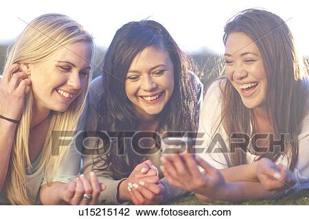 Three young women looking at mobile phone in park View Large Photo Image Stock Image - Three young women looking at mobile phone in park. Fotosearch