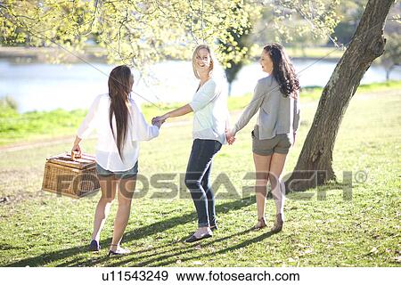 Three young women with picnic basket in park View Large Photo Image Stock Photo - Three young women with picnic basket in park. Fotosearch