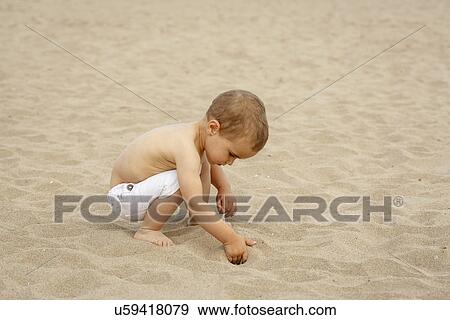 Toddler digging in sand with hand View Large Photo Image Stock Photo - Toddler digging in sand with hand. Fotosearch