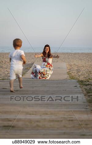 Stock Photo - Toddler running towards mother on boardwalk. Fotosearch