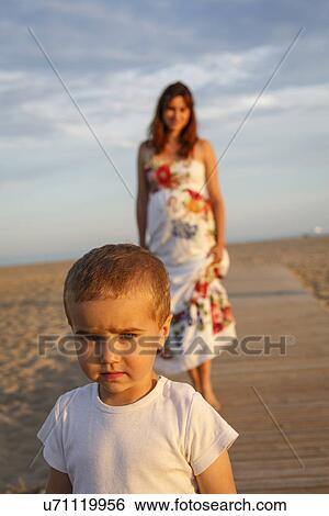 Toddler standing on boardwalk, mother in background View Large Photo Image Stock Photograph - Toddler standing on boardwalk, mother in background. Fotosearch