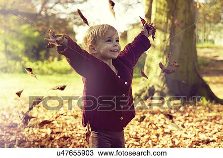 Stock Image - Toddler throwing autumn leaves. Fotosearch