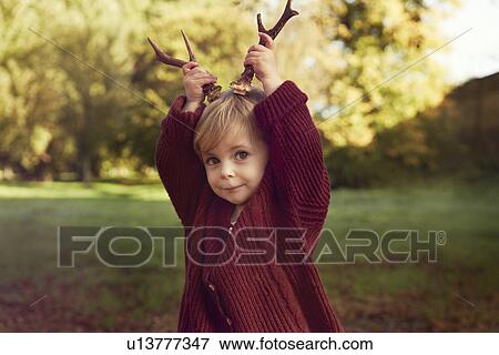 Stock Photo - Toddler using sticks as antlers. Fotosearch
