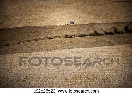 Stock Image - Tractor in field, Siena, Valle Orcia, Tuscany, Italy. Fotosearch