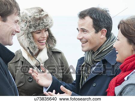 Stock Image - Two adult couples talking on beach, Thurlestone, Devon, UK. Fotosearch