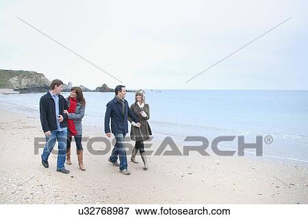 Stock Photo - Two adult couples walking on beach, Thurlestone, Devon, UK. Fotosearch