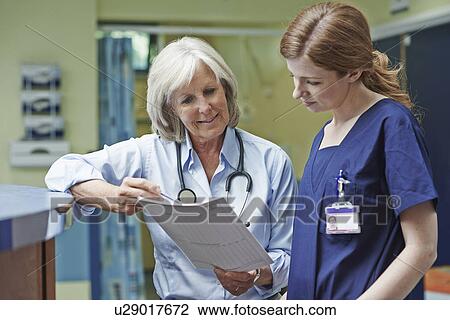 Two female doctors looking at medical record View Large Photo Image Stock Image - Two female doctors looking at medical record. Fotosearch