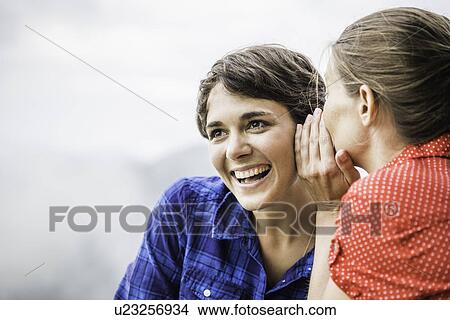 Two female friends sharing secret, Tyrol Austria View Large Photo Image Picture - Two female friends sharing secret, Tyrol Austria. Fotosearch