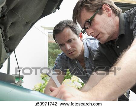 Two male adult friends checking under car hood View Large Photo Image Stock Image - Two male adult friends checking under car hood. Fotosearch