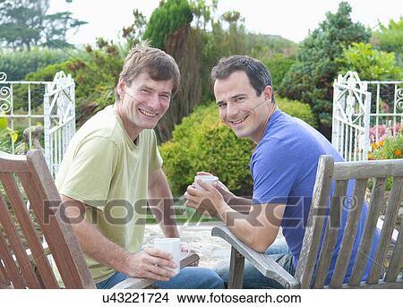 Two male adult friends relaxing in garden View Large Photo Image Picture - Two male adult friends relaxing in garden. Fotosearch