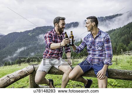 Two male friends drinking beer on fence, Tyrol Austria View Large Photo Image Stock Image - Two male friends drinking beer on fence, Tyrol Austria. Fotosearch