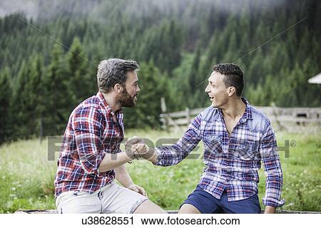 Stock Image - Two male friends shaking hands, Tyrol Austria. Fotosearch
