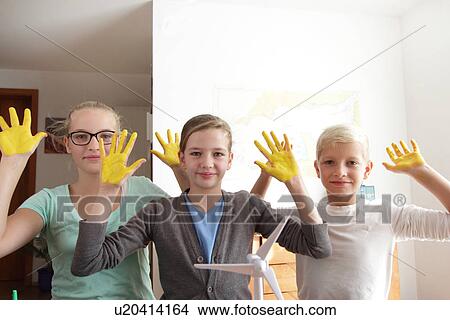 Two sisters and brother with yellow sunshine hands and a model of wind turbine View Large Photo Image Picture - Two sisters and brother with yellow sunshine hands and a model of wind turbine. Fotosearch