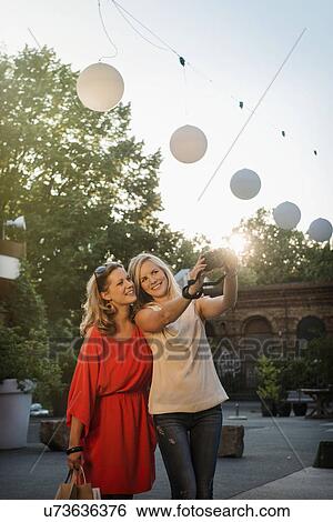 Stock Photograph - Two women taking self portrait, Berlin, Germany. Fotosearch