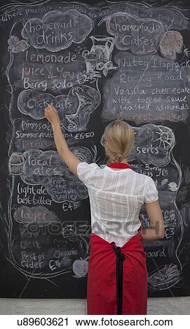 Waitress writing on blackboard menu in cafe View Large Photo Image Stock Image - Waitress writing on blackboard menu in cafe. Fotosearch