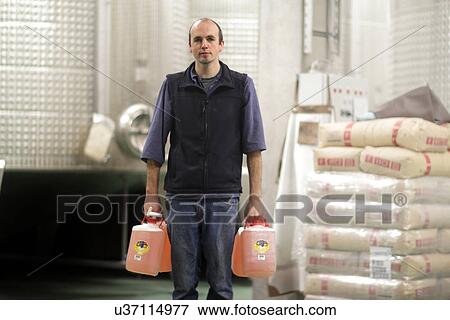 Stock Photo - Wine maker with bottles in industrial wine cellar. Fotosearch