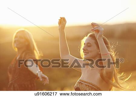 Stock Photo - Woman and teenager dancing in field at dusk. Fotosearch