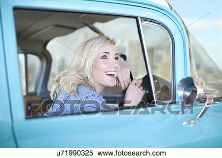 Stock Photography - Woman at wheels of vintage car looking up from window. Fotosearch