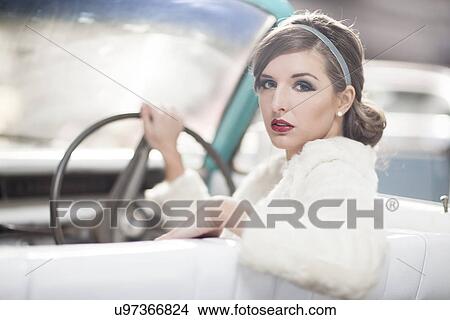 Woman at wheels of vintage car turning around View Large Photo Image Picture - Woman at wheels of vintage car turning around. Fotosearch