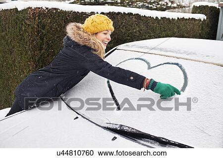 Woman drawing heart shape on snow covered windscreen View Large Photo Image Stock Image - Woman drawing heart shape on snow covered windscreen. Fotosearch