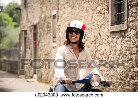 Stock Image - Woman exploring Florence on moped, Italy. Fotosearch