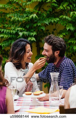 Picture - Woman feeding food to man at outdoor meal. Fotosearch