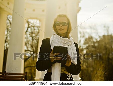 Woman holding digital tablet by stone pavilion View Large Photo Image Picture - Woman holding digital tablet by stone pavilion. Fotosearch