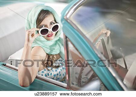 Woman in headscarf lowering sunglasses in vintage convertible View Large Photo Image Stock Photo - Woman in headscarf lowering sunglasses in vintage convertible. Fotosearch