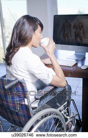 Woman in wheelchair drinking at computer View Large Photo Image Stock Photograph - Woman in wheelchair drinking at computer. Fotosearch