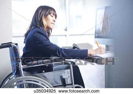 Stock Photography - Woman in wheelchair writing notes. Fotosearch