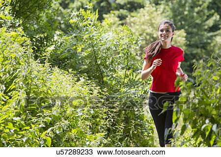 Woman jogging through forest View Large Photo Image Stock Image - Woman jogging through forest. Fotosearch
